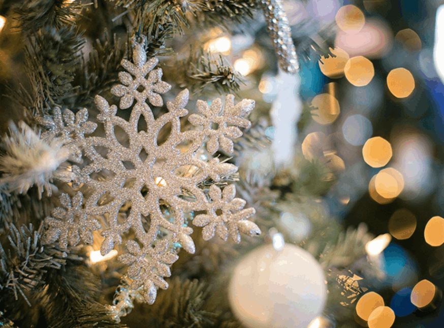 up_close_of_snowflake_ornament_on_lit_up_christmas_tree