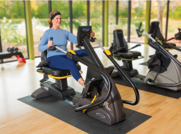 middle aged female exercising on a recumbent cross trainer in the gym