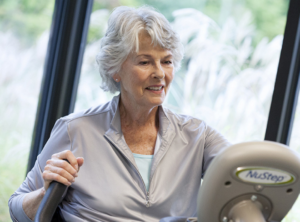 elderly_lady_smiling_while_exercising_on_a_nustep_seated_stepper