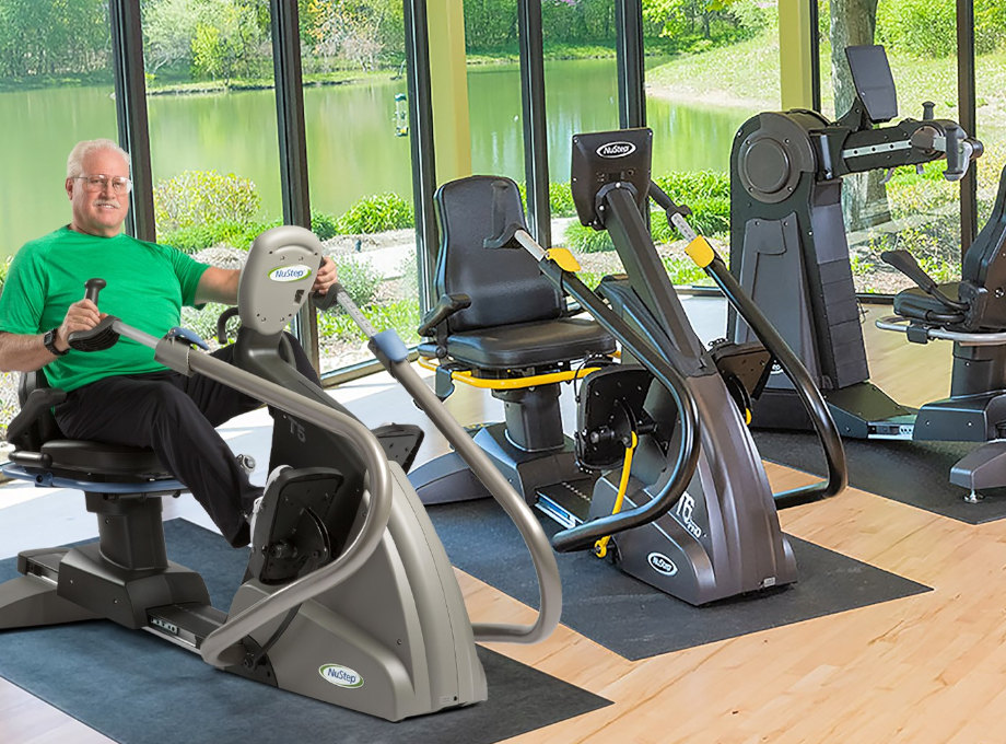 elderly_man_smiling_at_gym_exercising_on_low_impact_seated_stepper