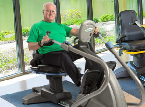 Older man on recumbent cross trainer exercising at home or in fitness center