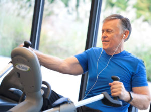 Older Man On Recumbent Cross Trainer Stepper Exercising at Gym