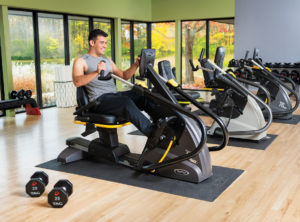 Younger Man on Seated Stepper Exercising in Home Gym Wellness Center