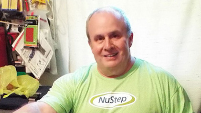 middle-aged-man-smiling-while-exercising-with-nustep-tshirt-on